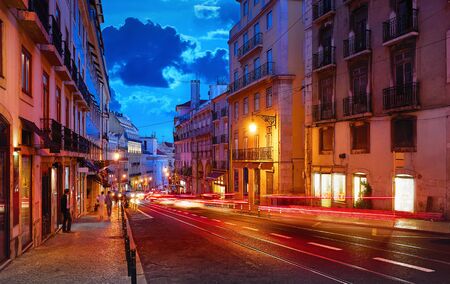 Porto, Portugal. Nighttime city life. Old town street with evening illumination and sky with clouds blue hour.の写真素材
