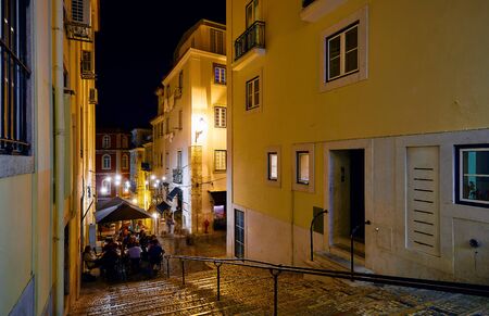 Lisbon, Portugal. Nighttime streets with stone stairs and restaurants under street lamps with evening illumination.の写真素材