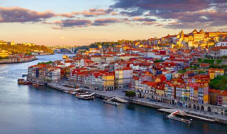 Antique town Porto, Portugal. Sunset sun over silhouettes skyline of roofs of houses along river.の写真素材