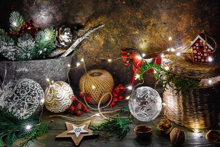 Christmas holiday decoration with fir, snow, balls and vintage toys with garland. Magical fairy-tale rustic composition with festive illumination on grunge and wooden board background.の写真素材