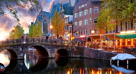 Red-light district in Amsterdam city picturesque landscape panorama evening town with pink sunset sky. Bridge over canal river Amstel.の写真素材