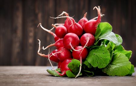 Bunch radish at background old board in rustic style. Close-up side view. Harvest fresh organic vegetables.の写真素材