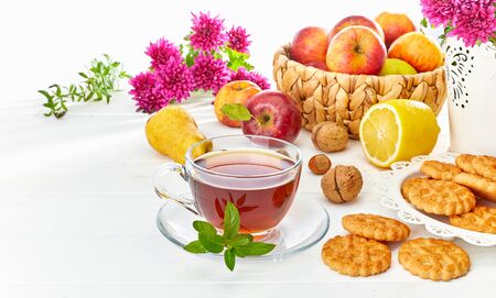 Tea with herbs fruits and cookies. Still life with hot drink apple and nuts at white wooden board in rustic style.の写真素材