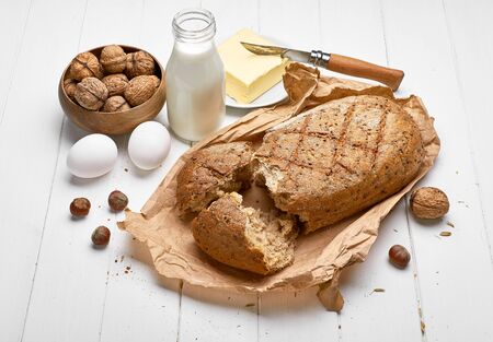 Fresh bread with crispy crust butter and milk at white wooden board in rustic style top view copyspace.の写真素材