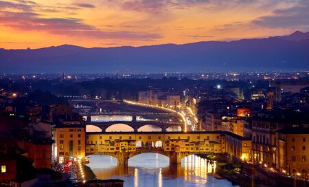 Evening sunset over Florence with Ponte Vecchio bridge on Arno river and tower in Italy.の写真素材