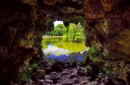 Park of Pleasant Retreat in Madrid Spain. Hole in stone cave with view on lake and trees. Picturesque landscape. Famous landmark. Tortoise in pond.の写真素材