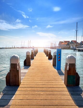 Volendam Amsterdam Netherlands. Sea bay. Wooden pier on North Sea with traditional houses at coast. Picturesque landscape with blue sky and white clouds.の写真素材