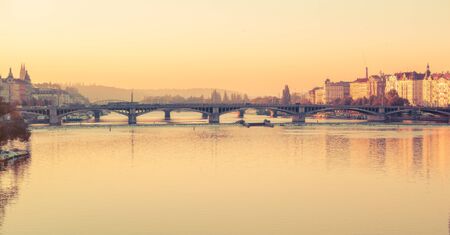Czech Republic Prague. View of river Vltava, house on coast and bridge. Picturesque urban morning landscape. Touristic landmark.の写真素材