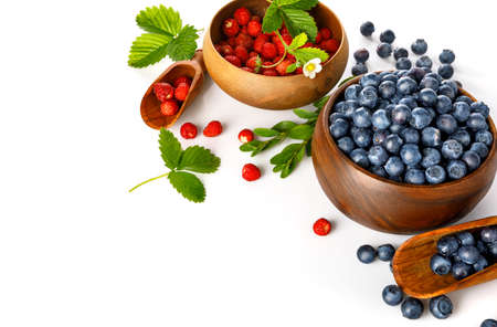 Berry blueberry and wild strawberry in wooden dish with green leaves and flower. Fruity still life. Healthy eating, isolated on white background.の写真素材