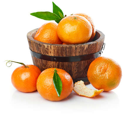 Harvest tangerines in wooden basket with green leaves. Fruity still life with fresh fruit. Isolated on white background.の写真素材