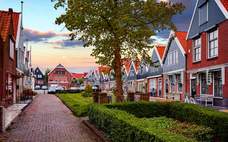 Romantic fishing village Volendam panorama in Netherlands, near Amsterdam. Small traditional houses by the cosy street. Evening sunset sky with clouds and moon.の写真素材