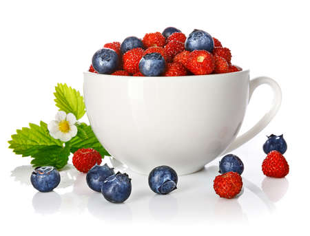 Berry wild strawberry and blueberry in cup with green leaf and flower. Fruity still life. Healthy eating. Isolated on white background.の写真素材