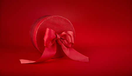 Gift with bow at red background. Side view. Festive postcard.の写真素材