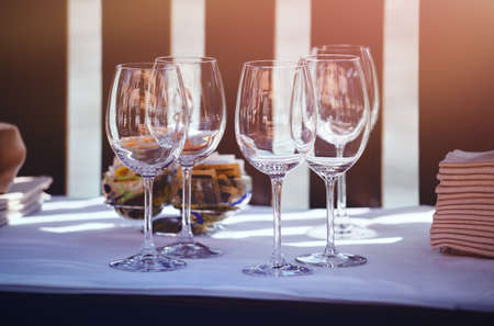 Glasses for wine on a served table ready for dinner. Glass of wine goblets with sunshine shadowsの写真素材