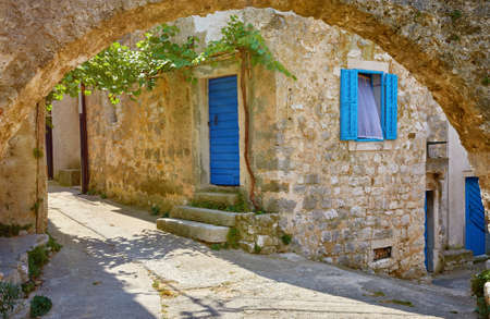 Croatia Istria. Ancient abandoned medieval town Plomin. Old stone street with ruined walls houses and stairs overgrown by ivy plants.の写真素材