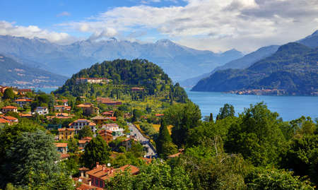 Bellagio village at lake Como, Italy. Panoramic view at hill with park and antique city among mountains and green forests. Summer picturesque landscape with water, waves and blue sky with clouds.の写真素材