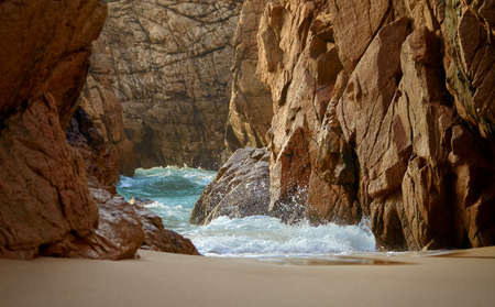 Beach at coast of Atlantic ocean in Portugal. Splashes of waves crashing of stone rocks.の写真素材