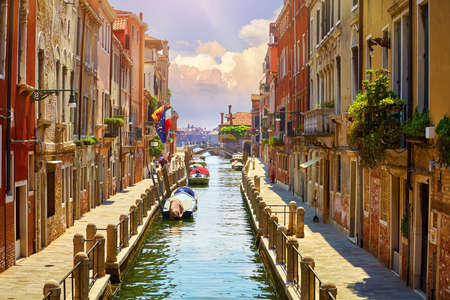 Venice, Italy. Boats, parked near brick walls of houses at street above water of channel. Sunny landscape. Summer day.の写真素材