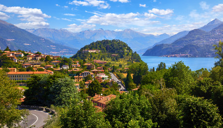 Bellagio village at lake Como, Italy. Panoramic view at hill with park and antique city among mountains and green forests. Summer picturesque landscape with water, waves and blue sky with clouds.の写真素材