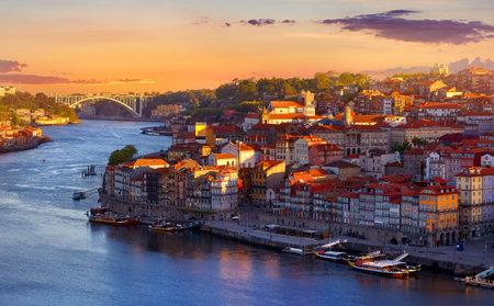 Antique town Porto, Portugal. Sunset sun over silhouettes skyline of roofs of houses along river.の写真素材