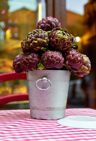 Artichokes in bucket vase on table with table-cloth. Decoration for street cafe tables outside in Rome, Italy. Close-up. Shallow depth of field.の写真素材