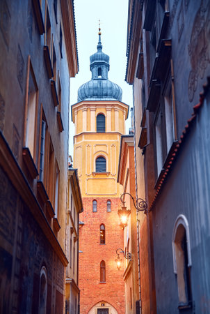 Warsaw Poland. Saint Martin Church in Old Town. High tower of the cathedral. Narrow street with lantern and evening illuminationの写真素材