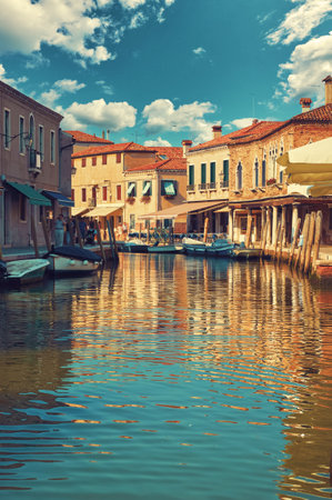 Island Murano in Venice Italy. Scenic view of canal with boats at the docks on the water. Picturesque landscape with traditional mediterranian architecture houses. Cosy street with motley buildingsの写真素材
