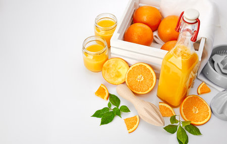 Fresh orange juice with fruits and green leaves in glass jars bottle on white background. Freshly squeezed for healthy lifestyle breakfast.の写真素材