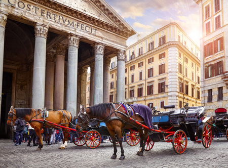 Rome, Italy. Horses in harness with coach for entertaining touristic strolls and city tours at Rotunda square (Piazza della Rotonda) front of Pantheon ancient roman building columns. Pantheon.の写真素材