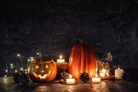 Halloween holiday. Pumpkin decoration with burning candles and jack-o-lantern face on dark rustic background copyspace place for textの写真素材