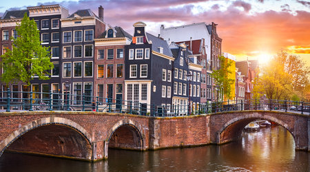 Amsterdam Netherlands. Traditional Dutch houses on river Amstel. Famous landmark. Old european city spring landscape with sunshine during sunset.の写真素材