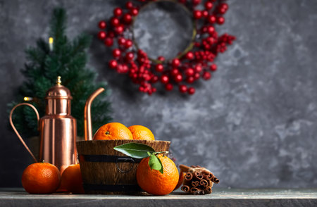 Still life with copper pitcher teapot and ripe fresh orange tangerine fruits in a wooden, barrel-shaped rustic bowl on bark wood table. Grunge stone wall berries wreath Christmas tree on background.の写真素材