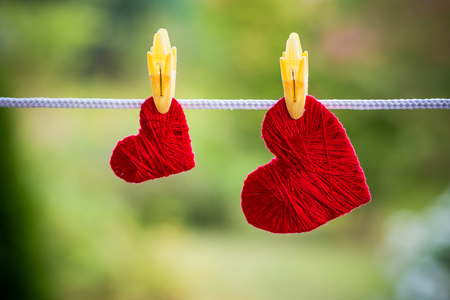 Two red hearts hanging on the rope fixed by clothespins isolated on blurred green background.Valentines Dayの写真素材