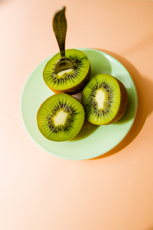 Kiwi fruits isolated on plate with dessert spoon, on pink background. Cut of green sweet kiwi. Detox, weight loss, eating vegetarian. healthy diet concept. copy spaceの素材 [FY310100557954]