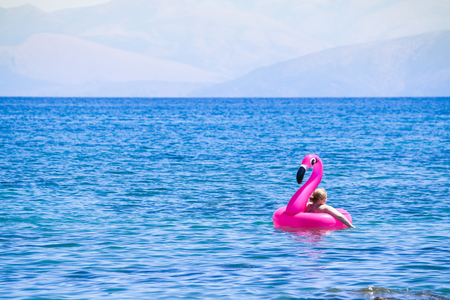 Girl having Fun with Flamingo rubber ring.Women wearing bikinis sitting on a rubber ring. Clear blue sea. Summer holidayの写真素材