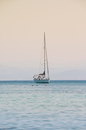 Sailing yacht race. Yachting. Sailing.Lonely yacht with white sail in open sea at sunset. Lonely boat. Blue Mediterranean sailboat sailing in perfect ocean. Copy spaceの写真素材