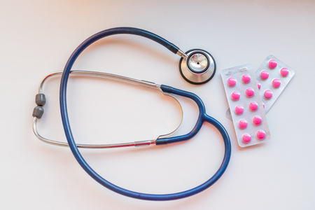 Stethoscope and some pink pills, medicine on a white background.Selective focus.pills different colors on white background. Health, heart conceptの写真素材