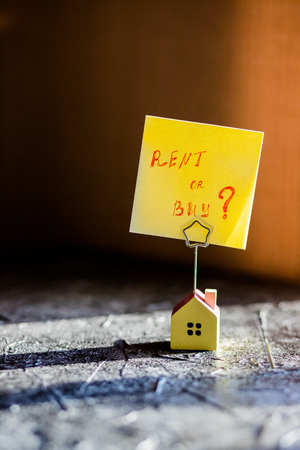 model of house as symbol on sunny background. Hand writing the text: Buy or Rent?の写真素材