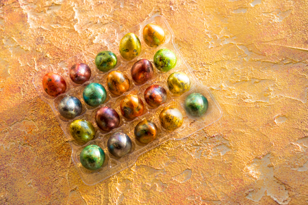Easter multicolored dyed bright quail eggs.Full pack of eggs corner on orange background. Top view. Copy spaceの写真素材