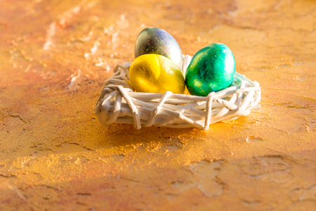 Bright, colorful Easter eggs in isolated on yellow.Background, multicolored easter eggs.Tree easter eggs in white nestの写真素材