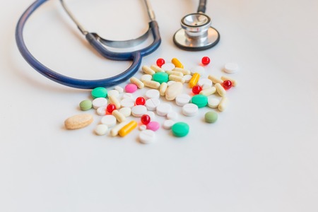 Medical theme. Stethoscope with pharmaceutical colorful pills and capsules on white background. Empty place for text. Top view. Flat design.の写真素材