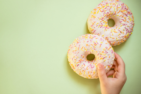 Sweet tasty snack. Hand hold glazed donut on white background top view copy spaceの写真素材