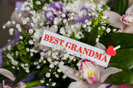 Beautiful flowers gift for Grandparents Day with greeting card. Top view, close-up. Congratulations for loved ones.bouquet of orchids for grandma. Best grandparents everの写真素材