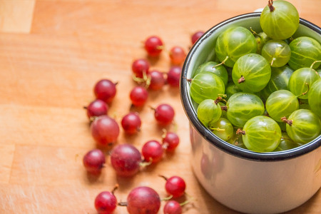gooseberries in a cup. Gooseberries fresh berries. red green gooseberry on wooden background.Different homemade summer berries. Selective focus. Copy spaceの写真素材