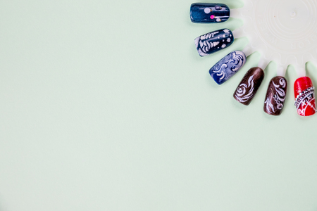 Manicure nail color design samples, winter holidays,winter party. Nail art handmade samples on a pastel background. Design templates for beauty salon. Selective focus. Copy spaceの写真素材
