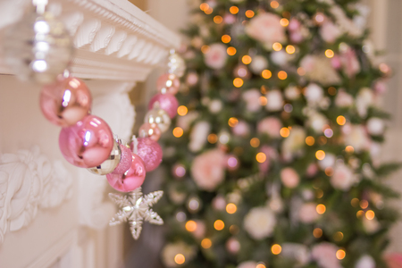 Christmas tree near fireplace in room.Pink balls garland and festive lights on the Christmas background with sparkles.christmas glitter bokeh background with golden twinkle lights. Merry christmas card. Winter holiday xmas theme.の写真素材