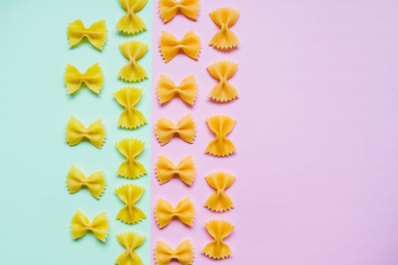 Frame from wheat pasta on pastel pink green background. Random pattern. Flat lay.Italian food concept.Bow tie Italian raw pasta fartalle pattern.Copy space. Diet and food concept.の写真素材