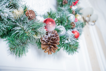 home Christmas decoration on white wall , fir branches, garland and pinecone, angel figure, christmas card with copy space on white wood surface. Christmas ornaments, new year ornaments.の写真素材