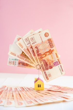 Mortgage loading real estate property with loan money bank concept.money and miniature house model isolated on pink background.Business, finance,saving money,banking ,house loan or insurance concept.russian money.の写真素材