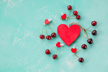 Heart symbol lined with red ripe cherries on a dark background. Concept of life. Style of a healthy...